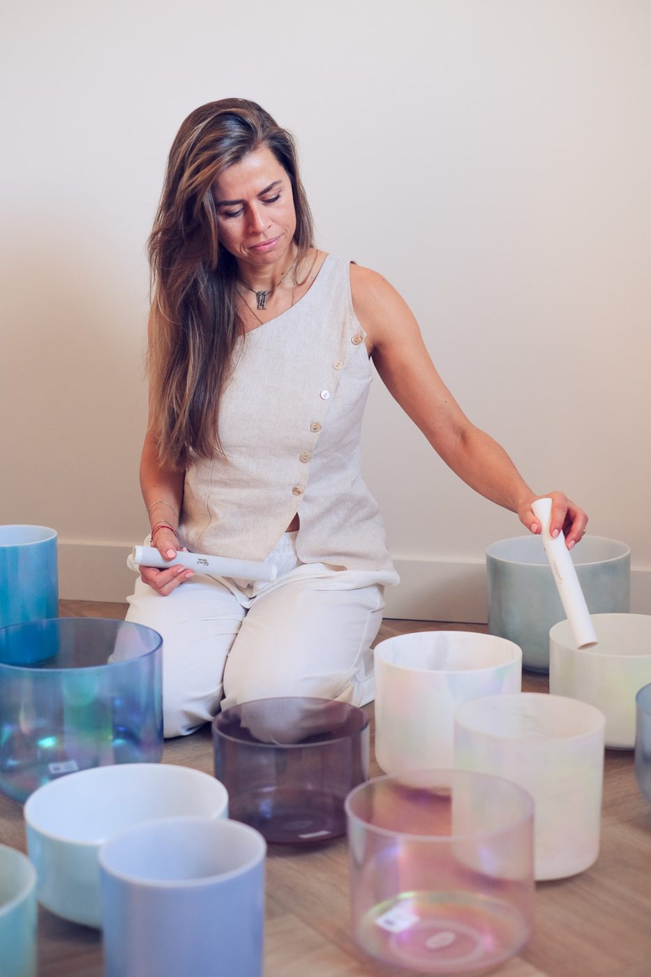 Lydia zit tussen haar kristallen klankschalen en bespeelt er een met een aanstrijker
